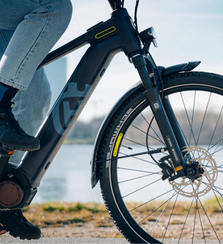 Detailed view of an electric bicycle with focus on the front wheel and fork, ridden by one person.